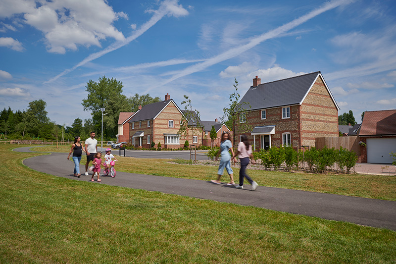 values-4 Families walking along a path past new brick homes on a sunny day